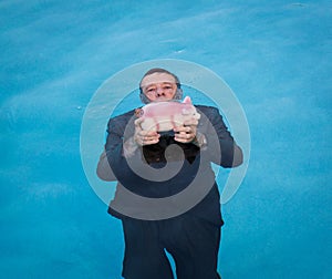 Senior man holding piggy bank above water