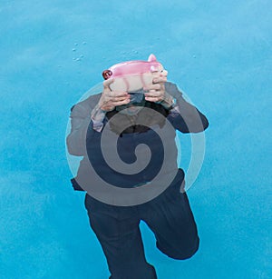 Senior man holding piggy bank above water photo