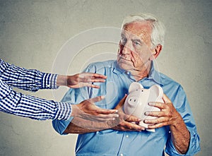 Senior man holding piggy bank suspicious protecting savings