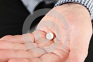 Senior man holding pill in hand