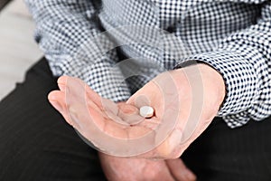 Senior man holding pill in hand