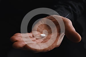 Senior man holding pill in his hand