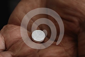 Senior man holding pill in his hand