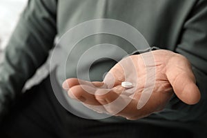 Senior man holding pill in his hand