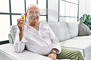 Senior man holding pills with a happy and cool smile on face