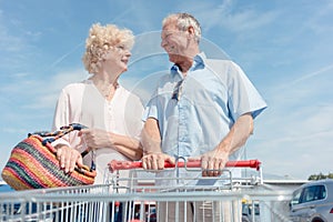 Senior man holding a shopping cart while looking at his wife with love