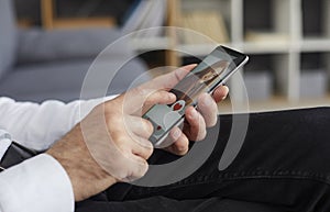 Senior man holding smartphone and giving a like to a young woman's photo on a dating app