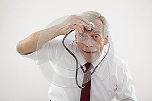 Senior man holding a stethosope to his forehead