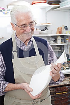 Senior Man Holding Vase In Pottery Studio