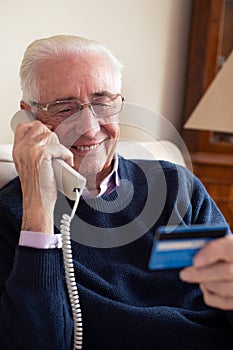 Senior Man At Home Giving Credit Card Details On The Phone