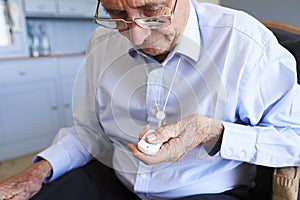 Senior Man At Home Using Distress Alarm Call Button