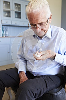 Senior Man At Home Using Distress Alarm Call Button