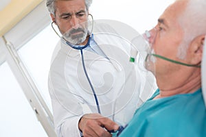 Senior man inhaling through oxygen mask in clinic