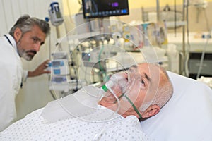 Senior man inhaling through oxygen mask in clinic