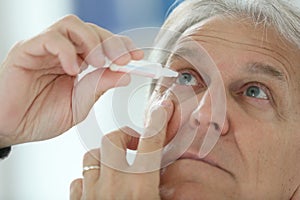 Senior man injecting serum in his eyes