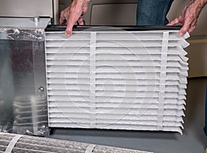 Senior man inserting a new air filter in a HVAC Furnace