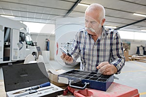 senior man inspecting tools in garage