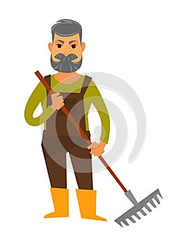 Senior man isolated in brown overall holds rake