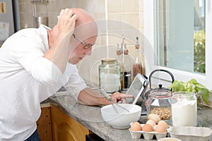 Senior man in kitchen using tablet
