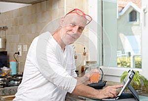 Senior man in kitchen using tablet