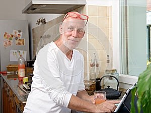 Senior man in kitchen using tablet