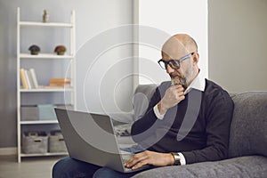 Senior man with laptop communicating online, working, consulting doctor or taking educational course at home