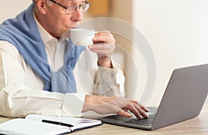 Senior Man At Laptop Drinking Coffee Working Sitting In Office