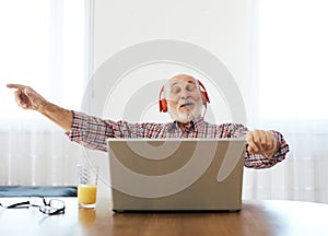 senior man laptop music listening mature elderly headphone earphone home technology