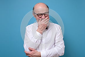 Senior man laughing and embarrassed giggle covering mouth with hands