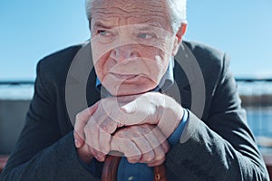Senior man leaning on cane and thinking of old times