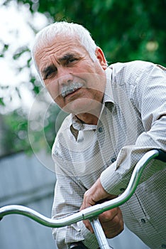 Senior man leaning on the handlebar of his bicycle