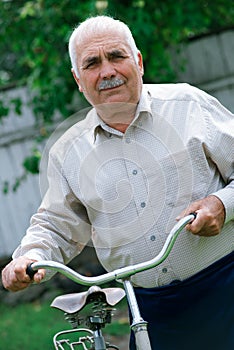 Senior man leaning on the handlebar of his bicycle