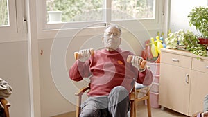 Senior man lifting dumbbells with difficulty in a nursing home