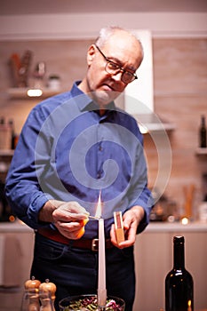 Senior man lighting candle with matches