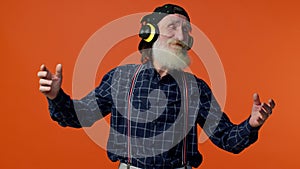 Senior man listening music on headphones dancing disco fooling around having fun gesticulating hands