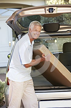 Senior Man Loading Large Package Into Back Of Car