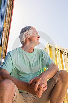 Senior man looking away while sitting at hut