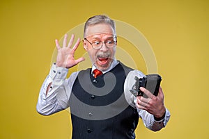 Senior man looking at camera while taking silly face selfie waving to the camera
