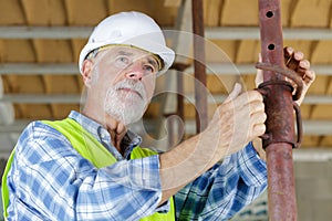 senior man looking through construction pipes