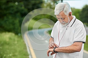 Senior man looking on handwatch during morning scamper.