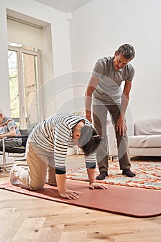 Senior man looking how his female friend doing morning exercises