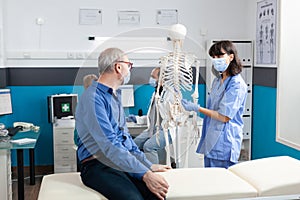 Senior man looking at human skeleton for chiropractic care