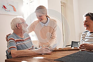 Senior man looking at the nurse embracing him while sitting