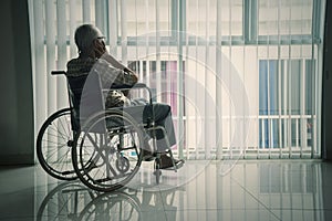 Senior man looking out the window in a wheelchair