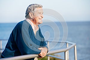 Senior Man Looking Over Railing At Sea