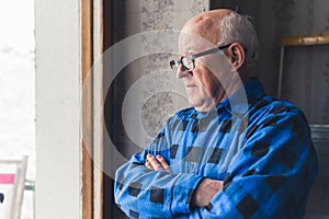 senior man looking seriously from the window medium closeup room seniority concept