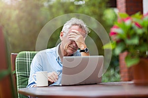 Senior man looking stressed while working on laptop