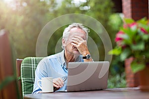Senior man looking stressed while working on laptop