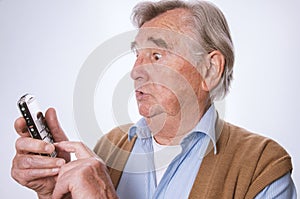 Senior man looking surprised and using his mobilphone photo