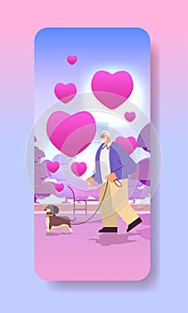 senior man in love walking in park with his little dog grandfather relaxing with pet valentines day celebration concept